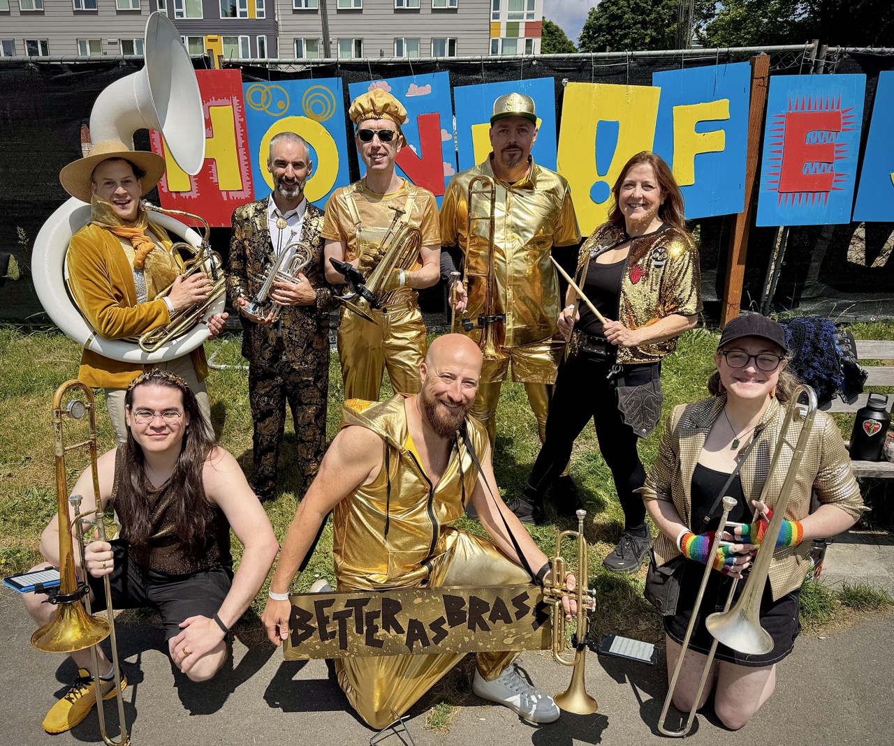 People posing for the camera with brass instruments and percussion dressed in metallic gold clothes.